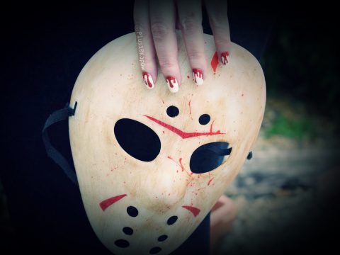 Chrissie's hand is holding a Jason Vorhees mask while wearing the Espionage Cosmetics Killer nail wraps